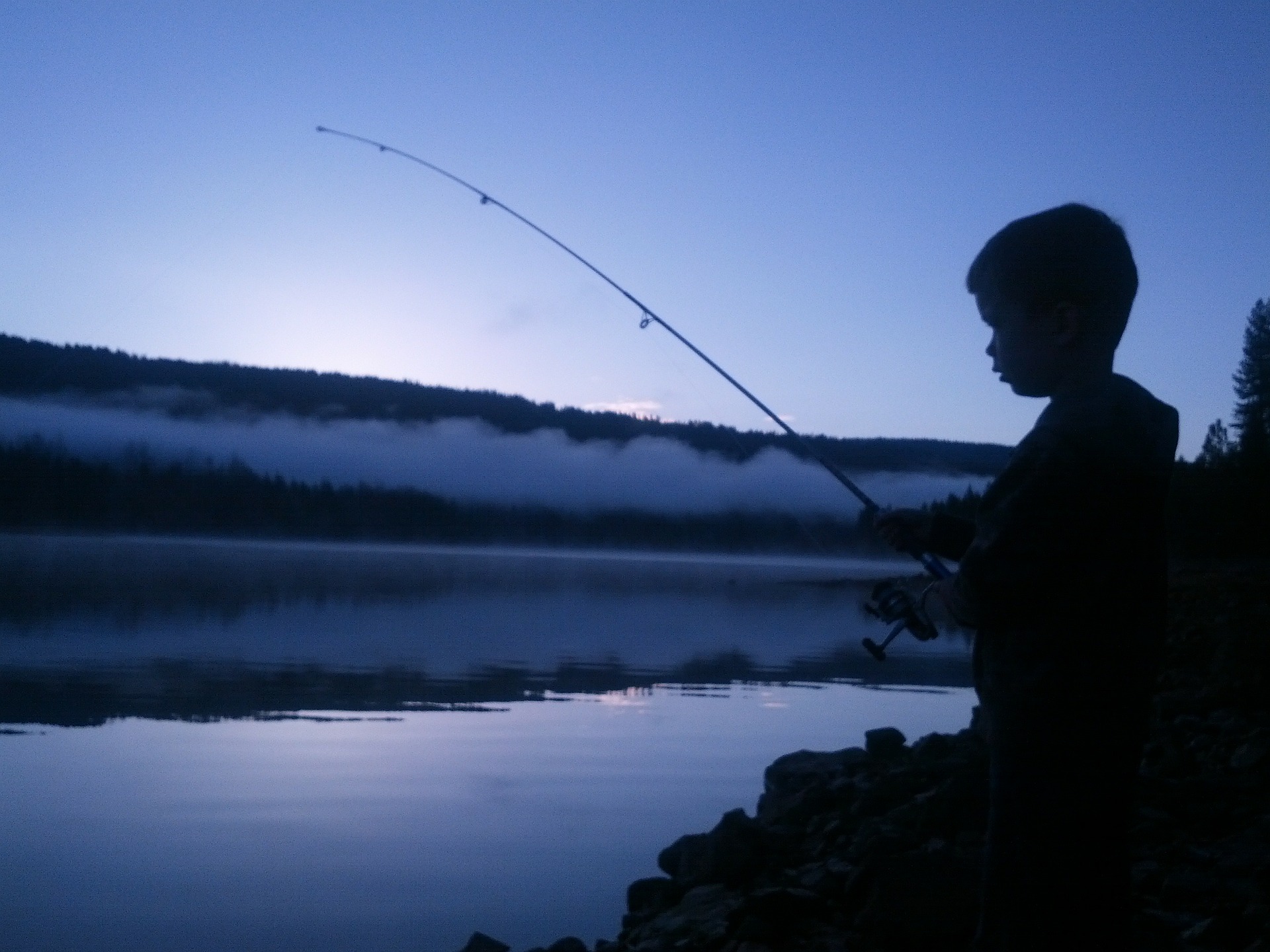 Dusk-silhouette-boy-fishing-canal.